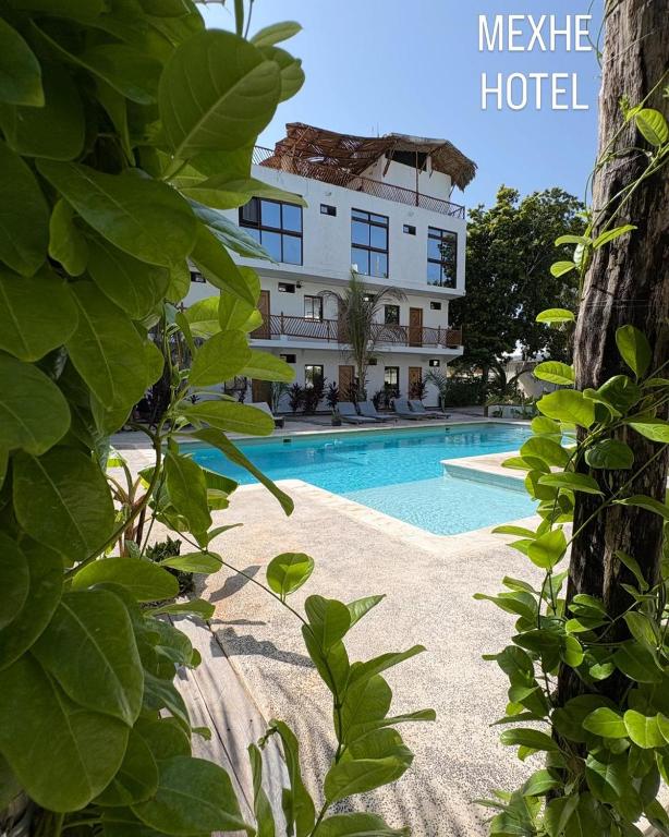 ein Hotel mit einem Schwimmbad vor einem Gebäude in der Unterkunft Mexhe Hotel El Cuyo in El Cuyo