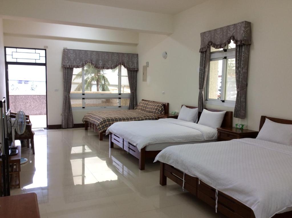 a room with three beds and a couch and windows at San He Inn in Taimali