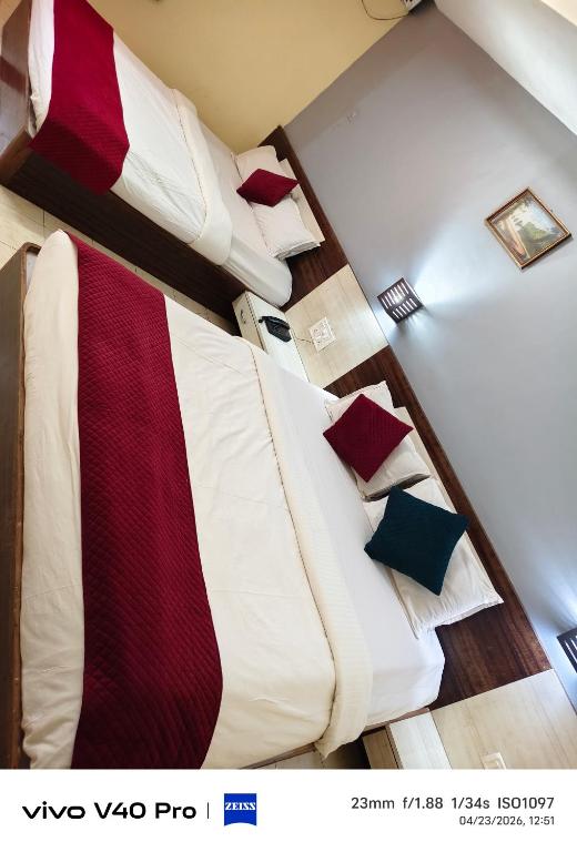 a bedroom with a bed with red and white sheets and pillows at Hotel HLD Matheran in Matheran