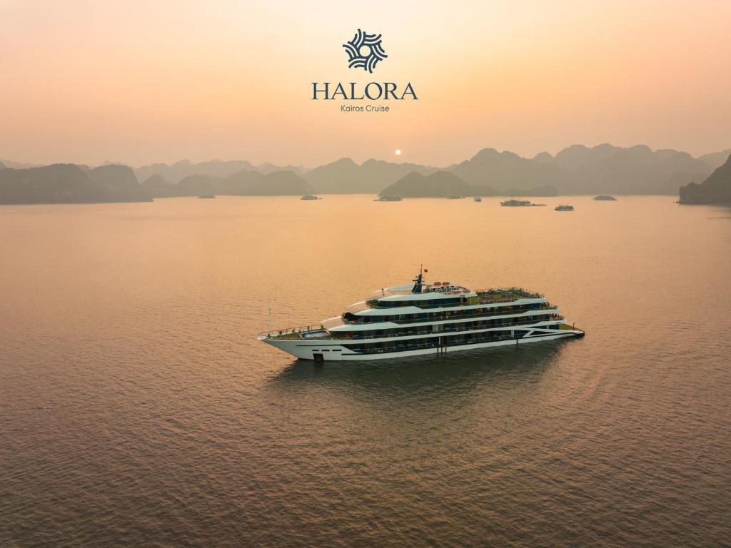 a large cruise ship in the water at sunset at Halora Kairos Cruise in Ha Long