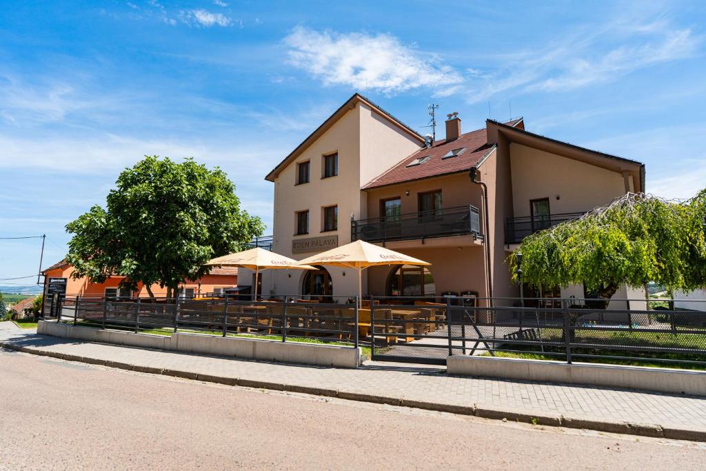 a building with tables and umbrellas in front of it at Penzion Eden Pálava in Klentnice