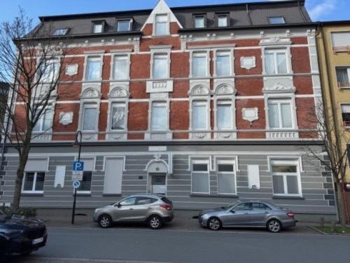 two cars parked in front of a large brick building at Hotel Jägerhof in Herne