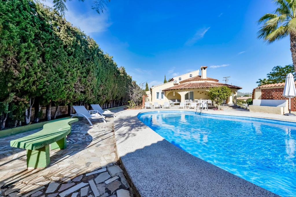 a swimming pool with chairs and a house at Villas Guzman - Xenia in Calpe