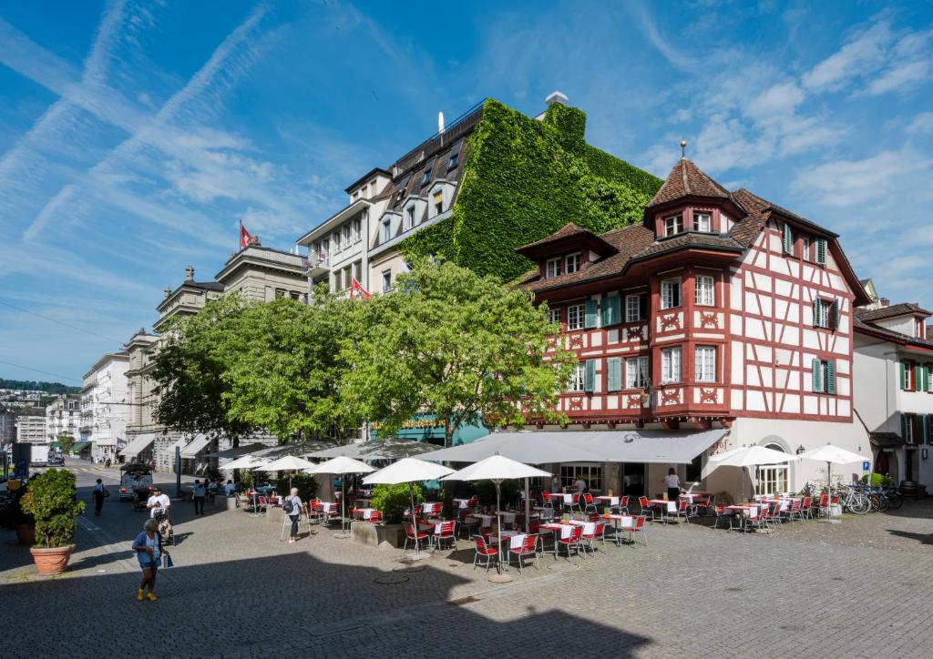ein großes Gebäude mit Tischen und Stühlen davor in der Unterkunft Hotel Rebstock in Luzern