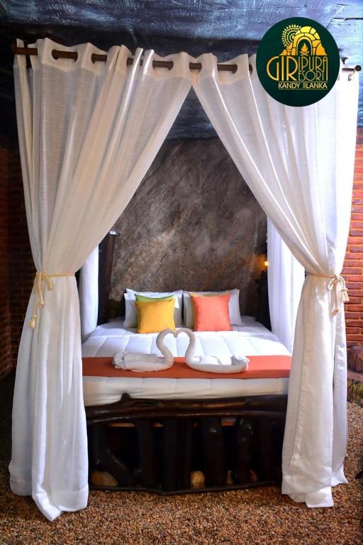 a bed with curtains and pillows in a room at Giripura Resort - Kandy in Kandy
