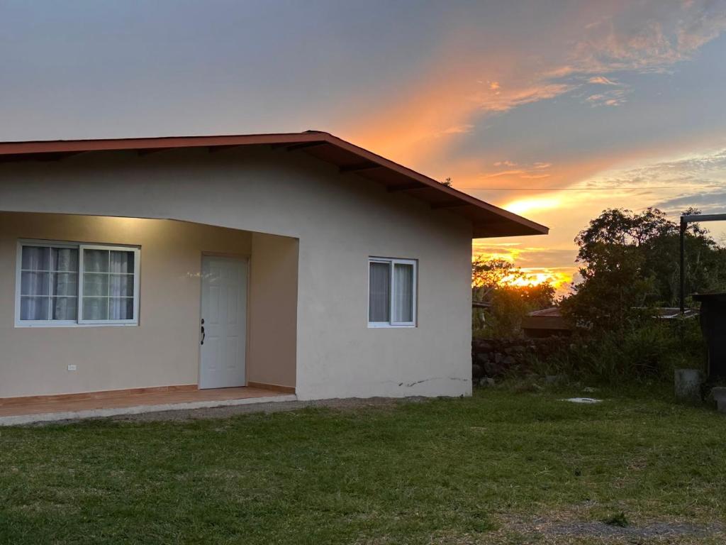 a small white house with a sunset in the background at California, Volcán, casa completa in Nueva California