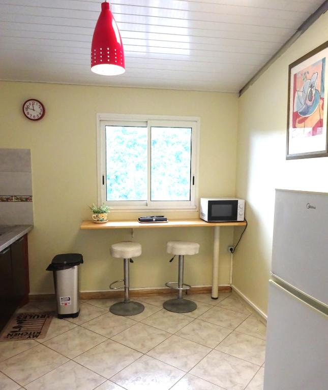 a kitchen with a counter with stools and a window at Le coin tranquille in Saint-Denis