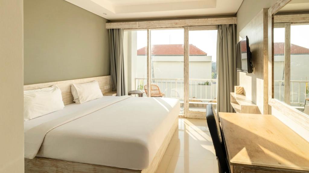 a bedroom with a large white bed and a window at Shashvata Berawa in Badung
