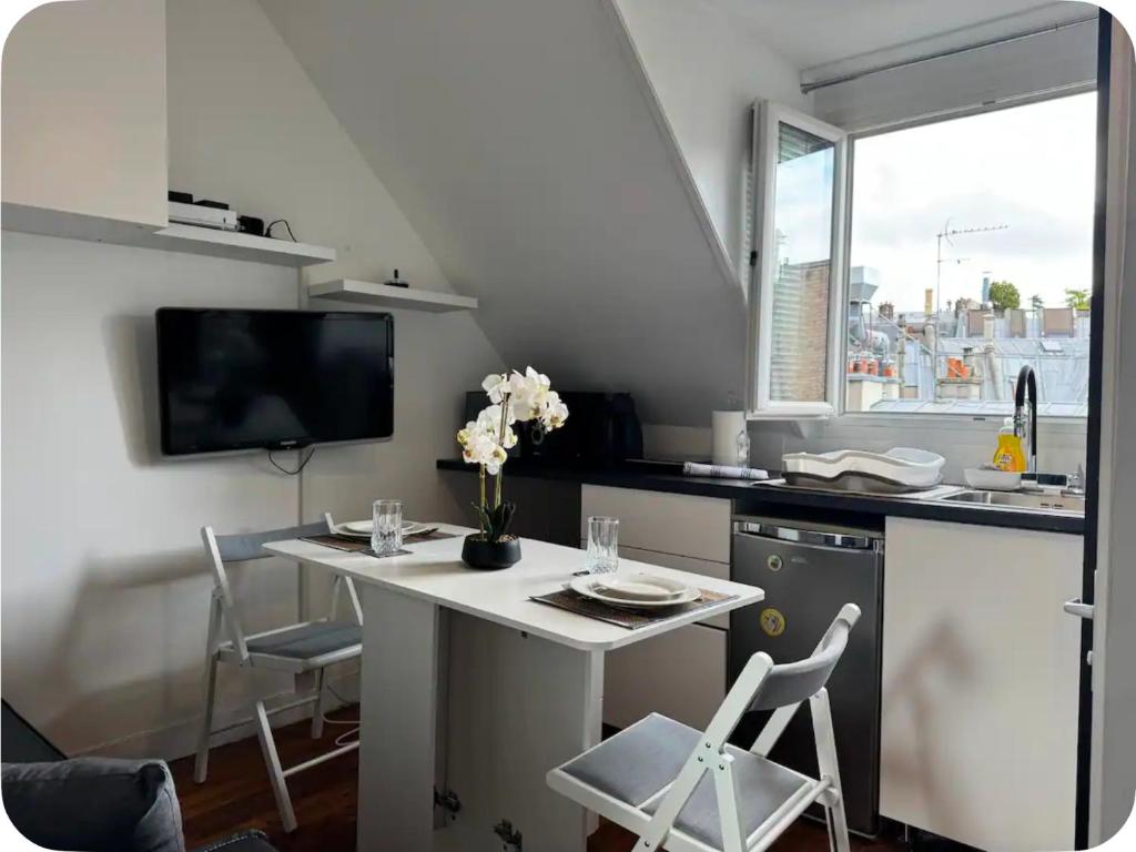 a kitchen with a white table and chairs and a tv at Residence Hôtel le Danoré Bastos in Yaoundé