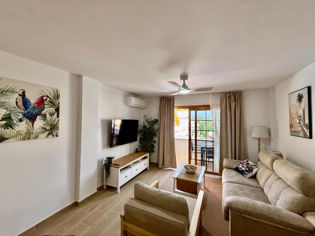 a living room with a couch and a tv at Pool View Apartment Garden City in Costa de Adeje