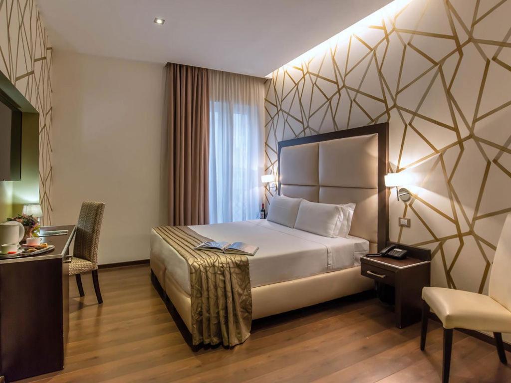 a hotel room with a bed and a table and a chair at Hotel Infinity San Pietro in Rome