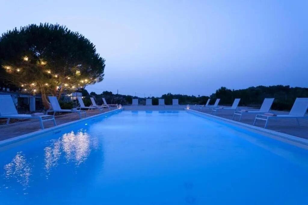 a large swimming pool with white lounge chairs at night at Masseria SoleMare Gallipoli in Pizzo