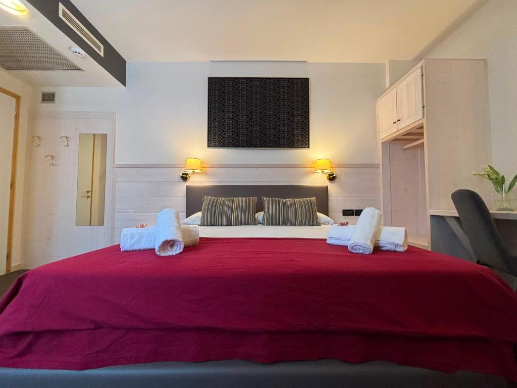 a bedroom with a large bed with a red blanket at Damodoro Hotel in Pordenone