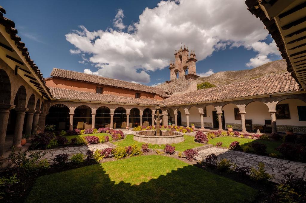 a courtyard with a fountain and a building with a clock tower at San Agustin Monasterio de la Recoleta in Urubamba