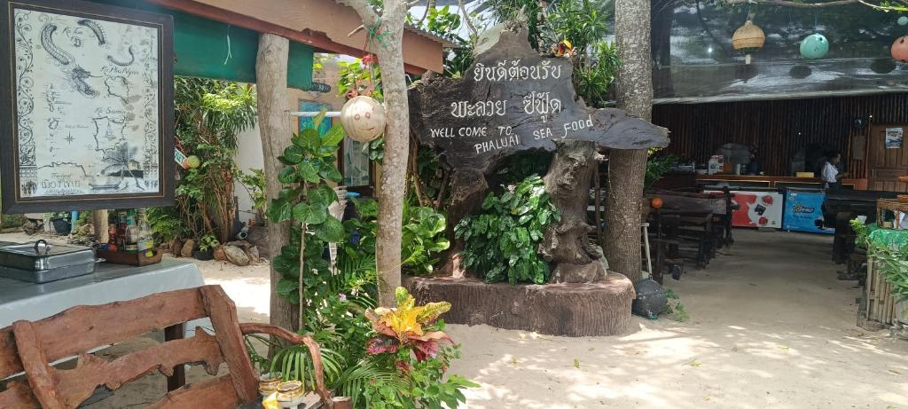 a restaurant with a sign and some plants at Phaluay seefood Motel in Koh Phaluai