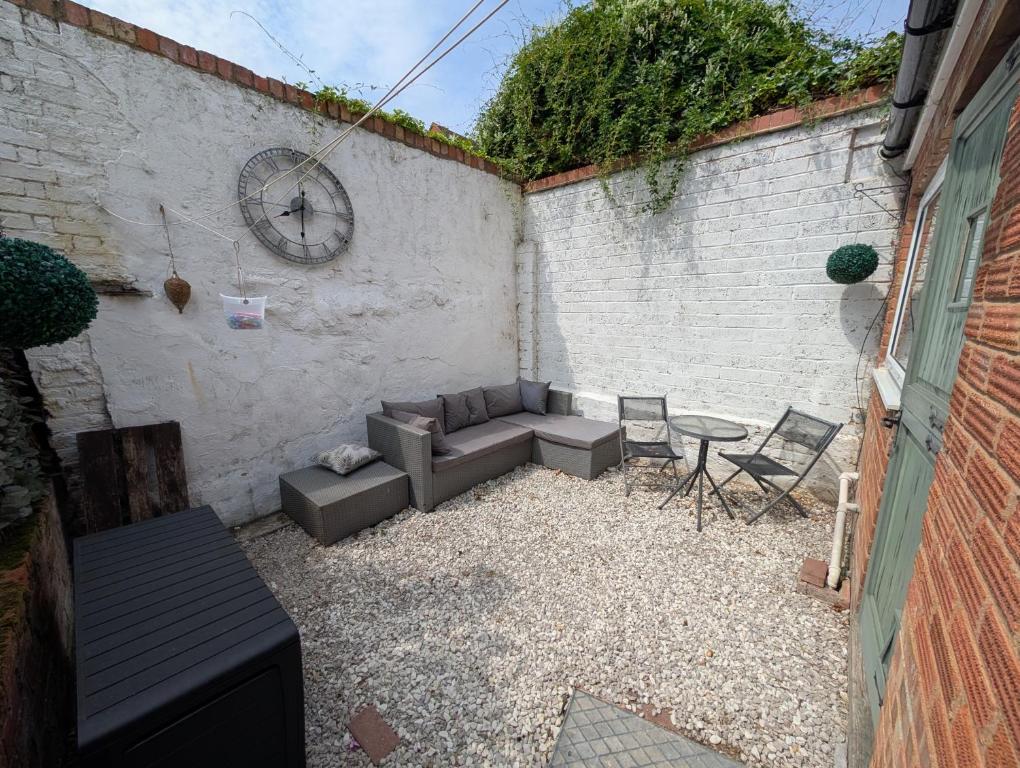 a patio with a couch and chairs and a clock at Quaint Cottage in Charming Evesham in Evesham