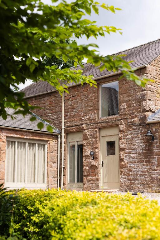a brick house with two windows and a door at The Byre in Penrith