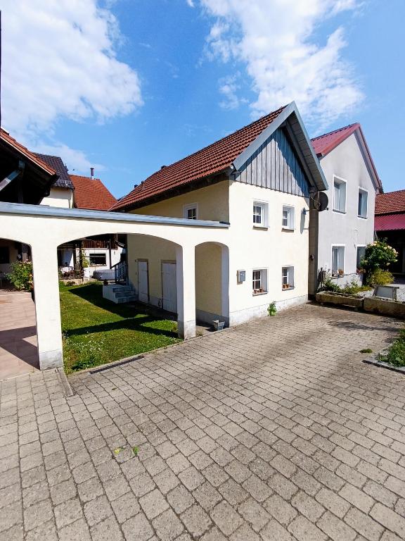 a large white house with a brick driveway at Tinyhouse Loisl in Thyrnau