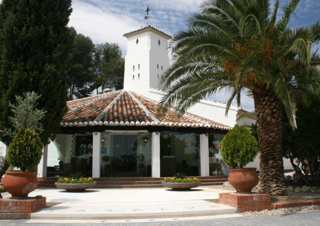 a church with a white tower and a palm tree at Hotel & Spa La Salve in Torrijos