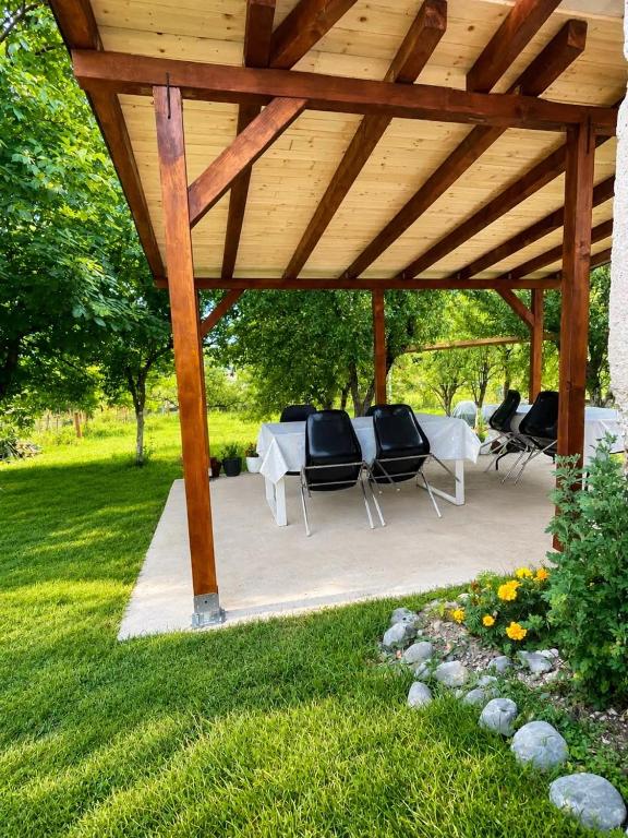 a wooden gazebo with a table and chairs under it at Guest House Ulnika in Vusanje