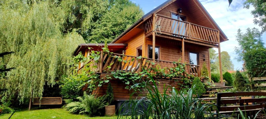 a log cabin with a porch and a balcony at Domek nad jeziorem in Olszyna