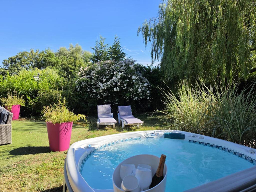 a hot tub in a yard with a bottle of champagne at La parenthèse du lac in Bevaix