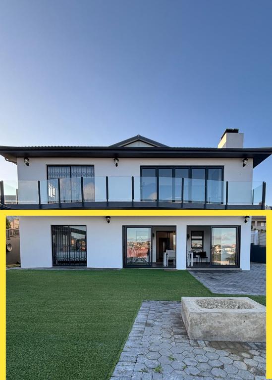 a large white house with a green yard at Seashell Flat in Mossel Bay