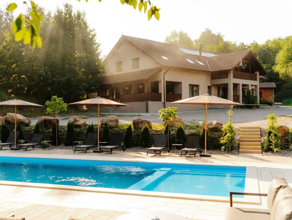 a house with a swimming pool with chairs and umbrellas at Transylvanian Relax House in Lupeni