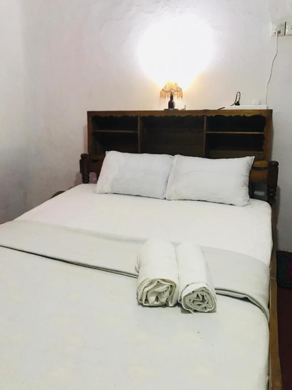 a bed with white sheets and towels on it at Sapphire Homestay in Palle Deltota
