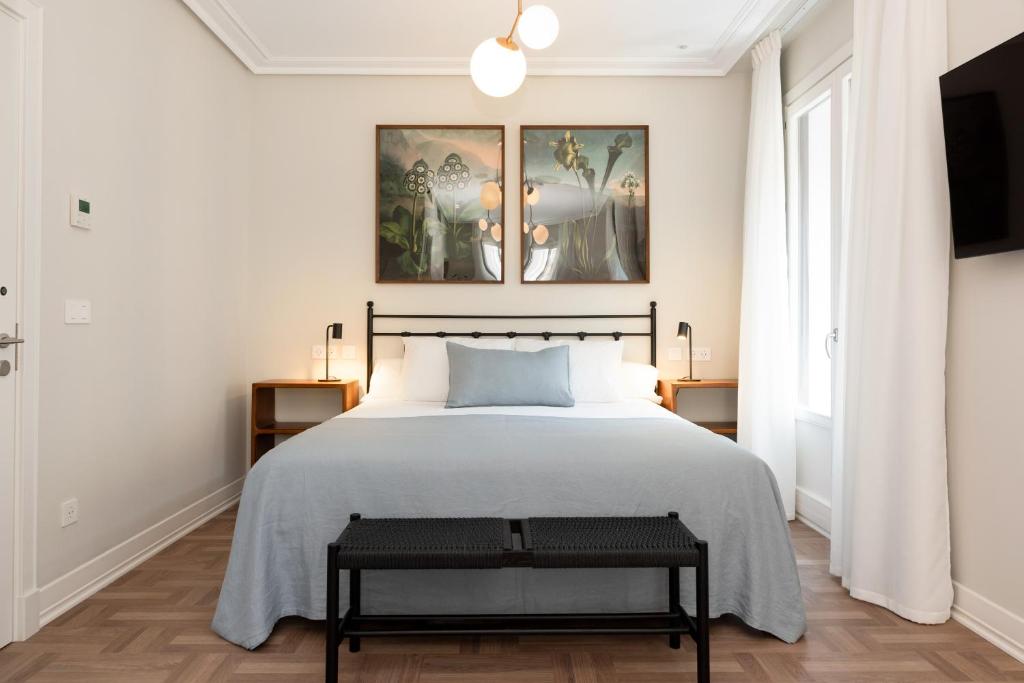 a bedroom with a large bed and two paintings on the wall at Hotel Sauce in Zaragoza