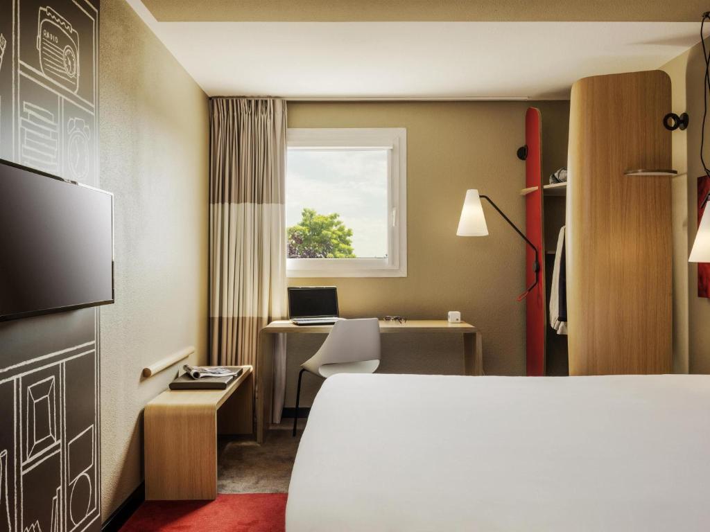 a hotel room with a bed and a desk and a window at ibis Massy in Massy