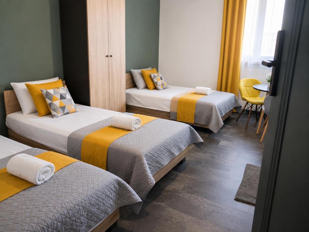 a room with three beds with yellow and gray at Komfortowe Apartamenty i Pokoje Powidz in Powidz