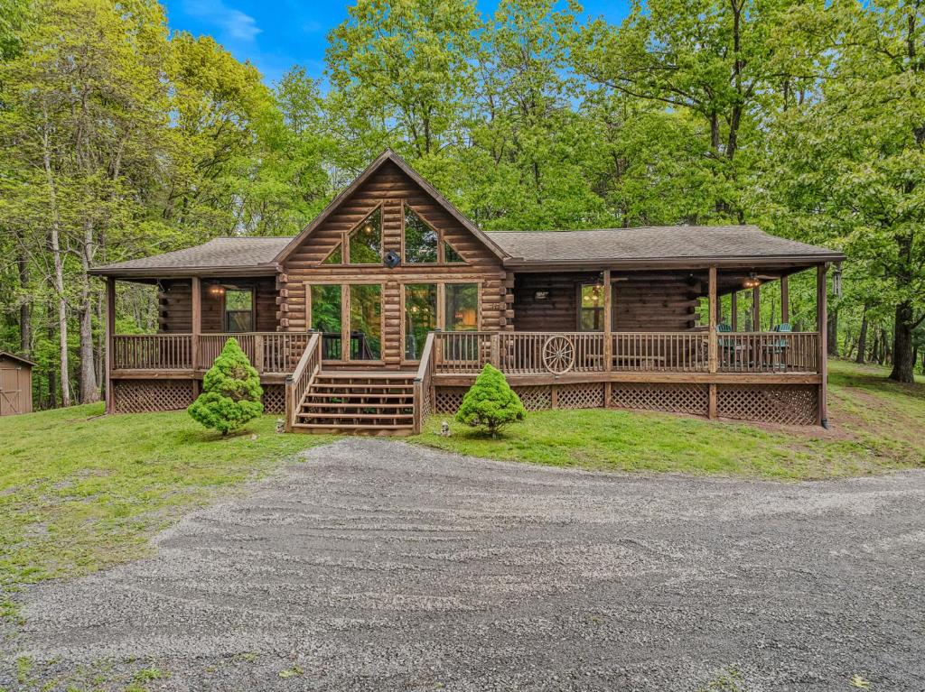 a log cabin in the woods with a driveway at Seventh Heaven - Hot Tub, Pet Friendly, Grill, Wifi, Deck, Covered Porch, Family Friendly, Kid's Loft, King Bed in Great Cacapon