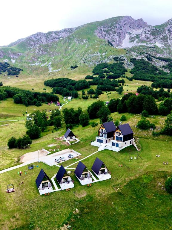 an aerial view of a house in a field with a mountain at Monte zone Zabljak in Žabljak