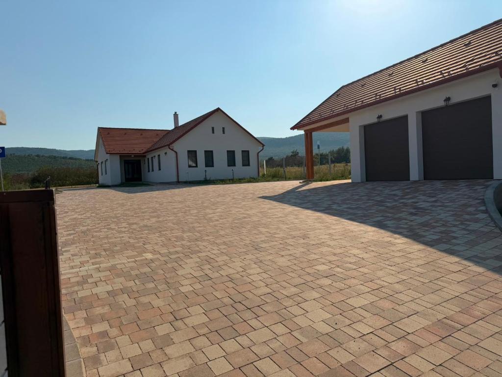 a brick driveway in front of two buildings at Mély-Patak Vendégház in Erdőbénye