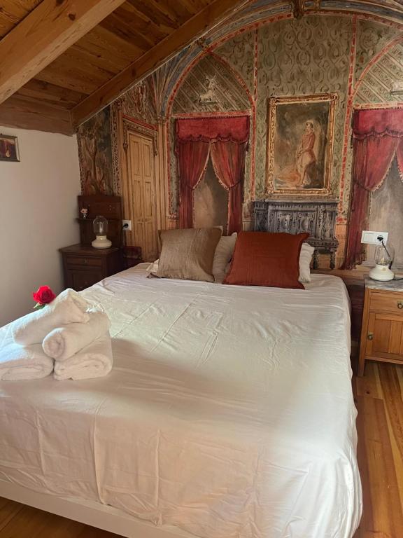 a bedroom with a large white bed with red curtains at La Alcoba de los Cuentos in Urueña
