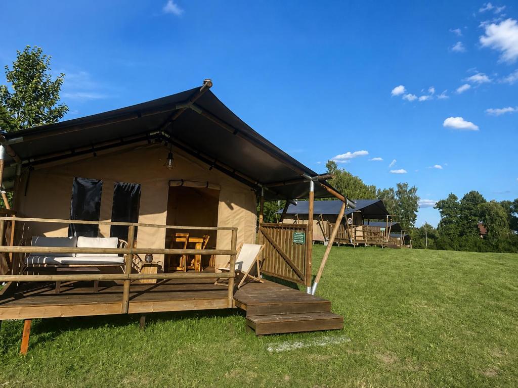 a cabin with a black roof on a grass field at Dworska Polana in Szteklin