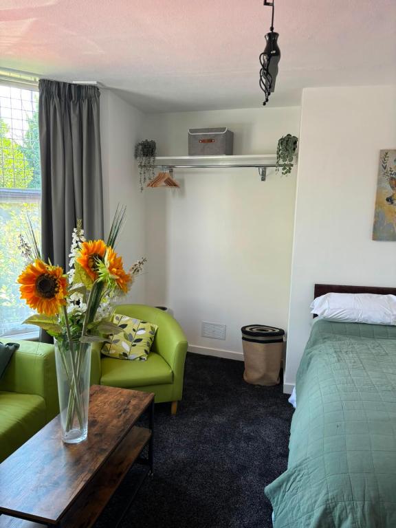 a room with a green couch and a vase with flowers on a table at Sunny and Comfortable Studio in Southport