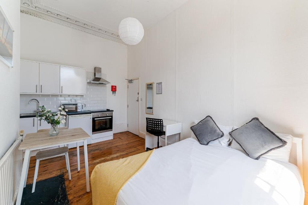 a white bedroom with a large bed and a kitchen at No 13 Georgian Shared House - By Clifton Short Lets in Bristol