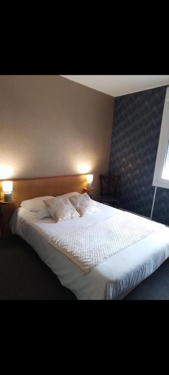 a bedroom with a large white bed with two lamps at Hôtel-Brasserie du marché in Saint-Pierre-du-Regard