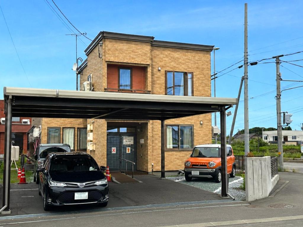 two cars parked in a parking lot in front of a building at House Villa Kagura in Asahikawa