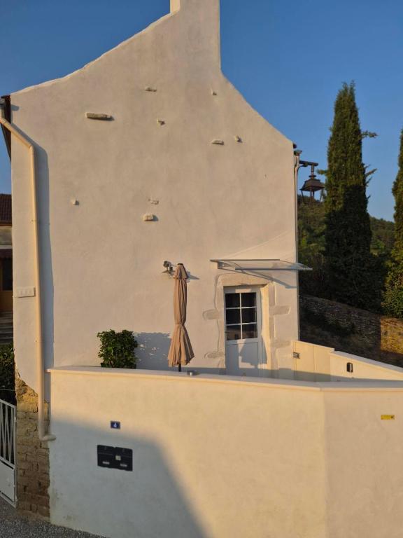 a white building with a umbrella on the side of it at Charmant gîte Au saut des vignes in Auxey-Duresses