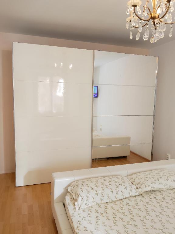 a white bedroom with a bed and a chandelier at Brasov Sfat Apartament in Braşov