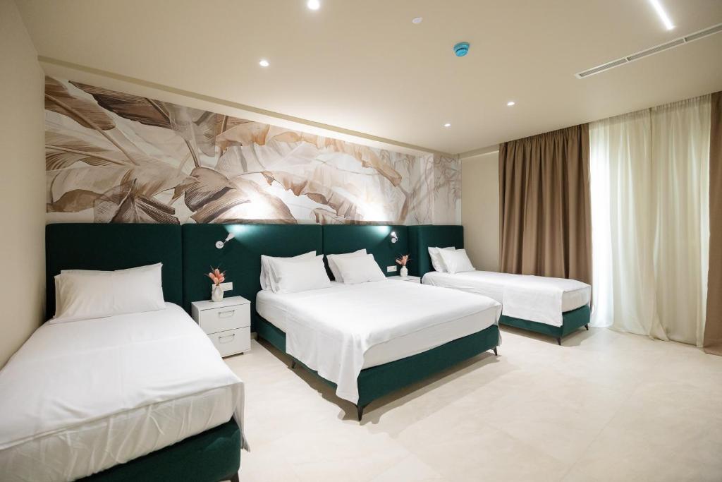 a bedroom with two beds and a painting on the wall at Otti Hotel in Vlorë