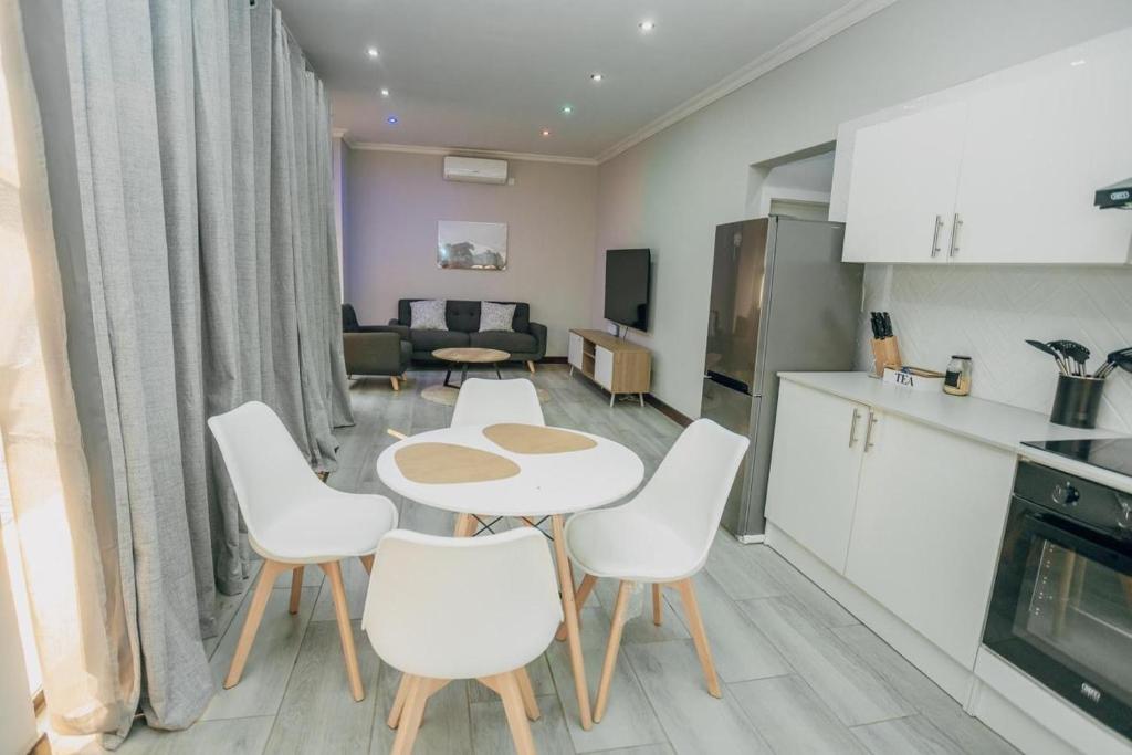 a kitchen and a living room with a table and chairs at Beck Apartments - Kitwe in Kitwe