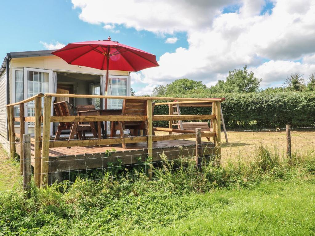 a house with a deck with a red umbrella at Hawks View Caravan in Macclesfield