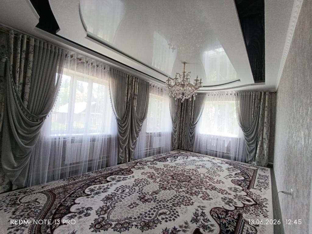 a bedroom with a bed with a chandelier and curtains at Baktygul in Karakol