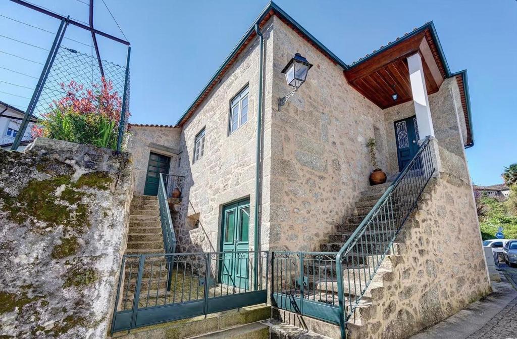 a stone building with stairs and a green door at Casa do Forno in Ponte da Barca