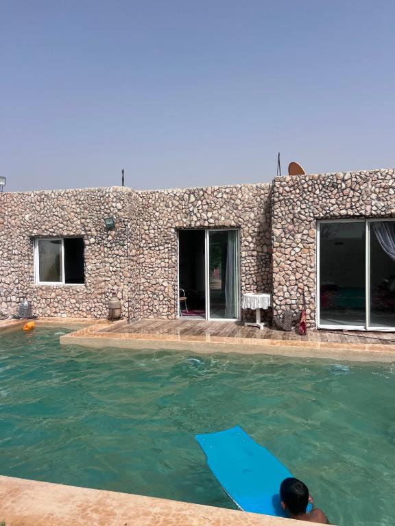 a person laying on a surfboard in a swimming pool at Villa compagne sans vis-à-vis in Ounara