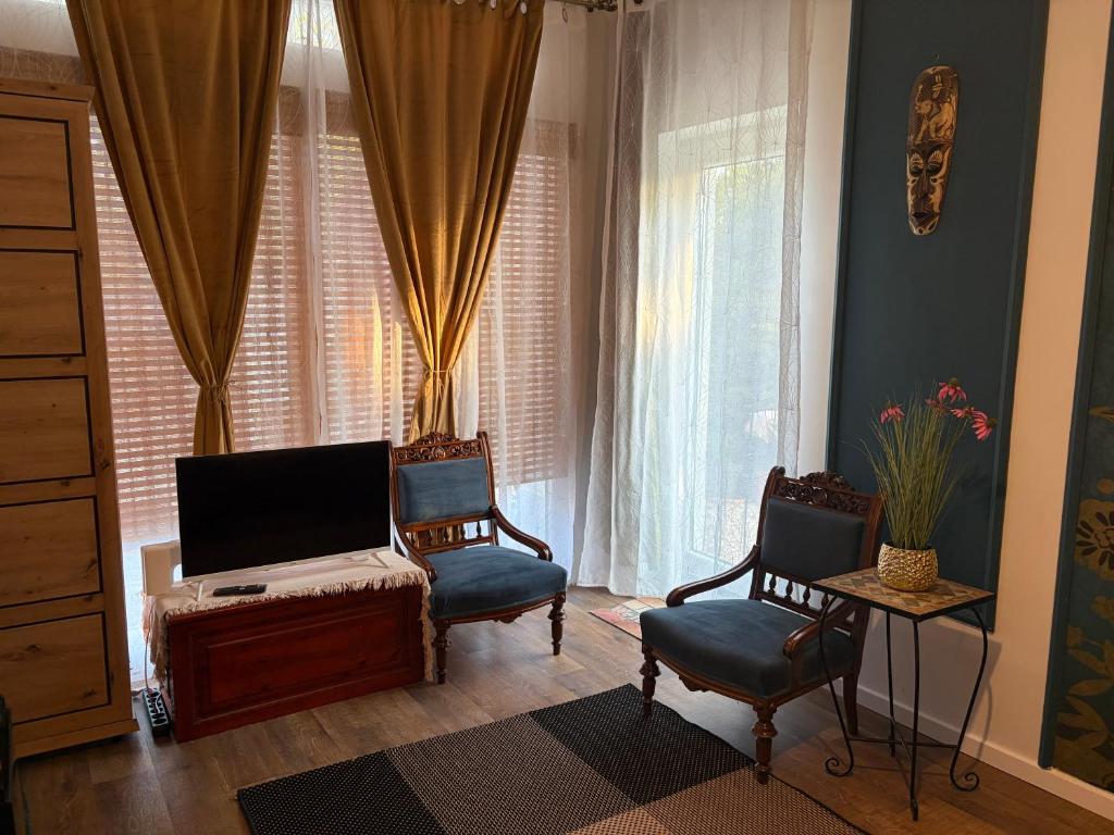 a living room with two chairs and a television at Villa Lavanda Vendégház & Spa in Gyulakeszi
